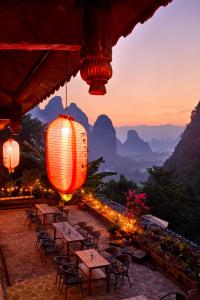 a group of tables with lights and mountains in the background at Yangshuo Yunshe Mountain Guesthouse in Yangshuo