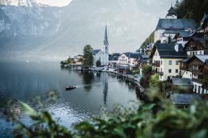 a small town on a lake with a church and a boat at Ferienwohnung SeeTraum Hallstatt in Hallstatt