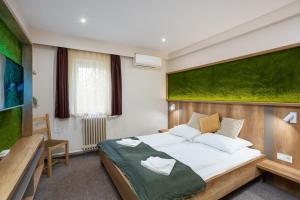a bedroom with a large bed with a green wall at Bauer Resort Countryside Retreat in Röszke