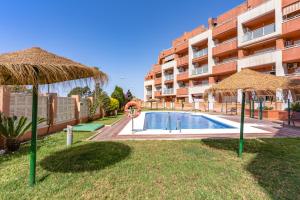 un complejo con piscina y 2 sombrillas en Mediterráneo Studio R&R, en Roquetas de Mar