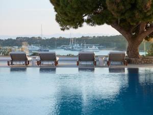 a group of benches sitting next to a body of water at The Roc Club, A Grecotel Hotel to Live in Athens