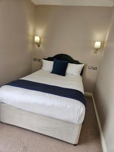 um quarto com uma cama grande com lençóis brancos e azuis em Owston Hall Hotel em Doncaster