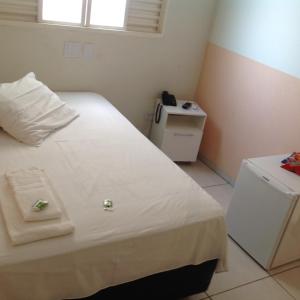 a small bedroom with a white bed and a table at Hotel Village Premiun in Bebedouro