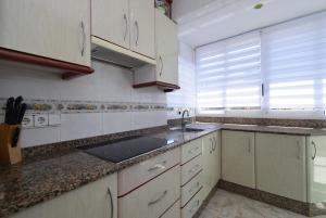 Una cocina con gabinetes blancos y un fregadero. en ALBATROS - Fincas Arena, en Benidorm