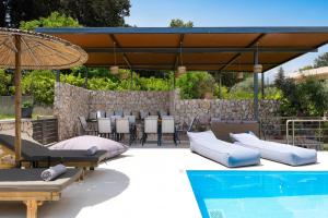 a patio with pillows and an umbrella next to a pool at GGA Albatross Villa in Afantou