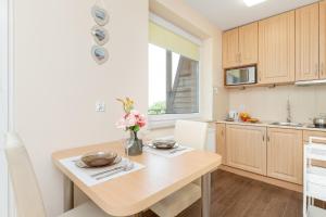 a kitchen with a table with a vase of flowers on it at Wakacyjny Apartament z Parkingiem 500 m od Plaży by Noclegi Renters in Puck