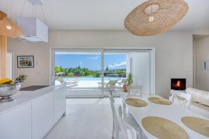 a white kitchen and dining room with a table and chairs at Villa Menta 4 in Malinska
