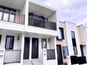 a white building with black doors and a balcony at New townhouse with garden in the city centre in Auckland +3 photos