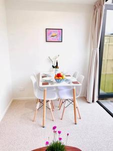 a white dining room with a table and chairs at New townhouse with garden in the city centre in Auckland