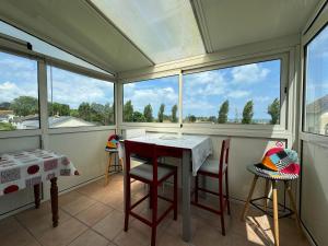 a screened in porch with a table and chairs at Maison vue mer 4 personnes in Arromanches-les-Bains +15 photos