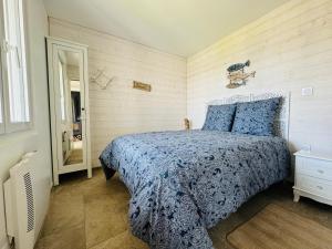 a bedroom with a bed with a blue comforter at Maison vue mer 4 personnes in Arromanches-les-Bains