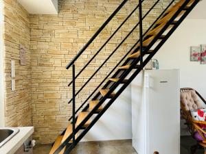 a wooden staircase in a kitchen with a brick wall at Maison vue mer 4 personnes in Arromanches-les-Bains