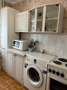 a kitchen with a washing machine and a microwave at Economy - class apartment in Pavlodar