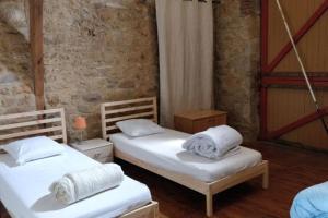 2 camas individuales en una habitación con una pared de ladrillo en Grande maison, avec piscine privée et belle vue, en Ambeyrac 29 fotos más