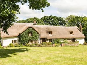 athatched house with a thatched roof on a field at Hay Meadow Farm, Cosy Thatched Holiday Cottage in Beaworthy