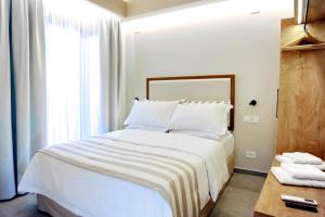 a bedroom with a bed with white sheets and a window at Demar Suites Vlycho Lefkada in Vlikhón