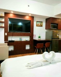 a bedroom with a bed with a flat screen tv at 212B Amani Grand Resort Residences near Mactan Airport with pool, gym, wifi, netflix in Pusok
