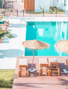 - une piscine avec 2 chaises et un parasol à côté de la piscine dans l'établissement Shambhala Fuerteventura, à Parque Holandes