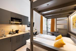 a room with a bed and a sink and a kitchen at Servus Apartments by Homaris in Munich