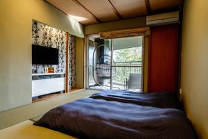 Schlafzimmer mit einem Bett und einem Balkon mit einem TV in der Unterkunft YuYu Hakone - Private Open Air Onsen Usage Guaranteed in Hakone