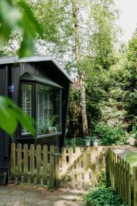 a black tiny house behind a wooden fence at Tiny Cabin Mae op de Veluwe in Putten