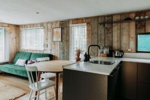 a kitchen with a sink and a table and a couch at Tiny Cabin Mae op de Veluwe in Putten +7 photos
