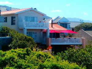 a house with a balcony with a red umbrella at Belle Vue Guesthouse in Hermanus