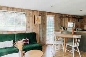a living room with a green couch and a table at Tiny Cabin Mae op de Veluwe in Putten