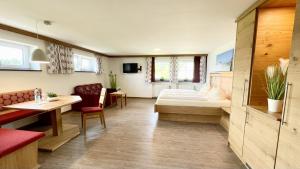 Habitación de hotel con cama, mesa y sillas en Landhotel Schwarzenbach - Wellness & Spa, en Rieden