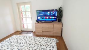 a living room with a television on a wooden dresser at Viszontlát-Lak Békésszentandrás in Békésszentandrás +19 photos