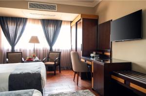 カイロにあるMarwa Palace Hotel Cairoのベッド、デスク、ピアノが備わるホテルルームです。