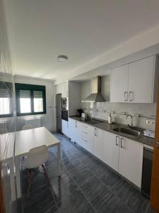 a kitchen with white cabinets and a table and a sink at PortoHome 1 in Portomarin