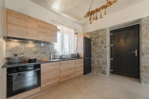 een keuken met houten kasten en een zwarte deur bij Naxos Privilege Villas in Agia Anna Naxos