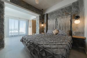 een slaapkamer met een groot bed en een stenen muur bij Naxos Privilege Villas in Agia Anna Naxos