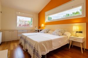1 Schlafzimmer mit einem großen weißen Bett und 2 Fenstern in der Unterkunft Casa con jardín próxima a Barcelona in Sant Andreu de Llavaneres