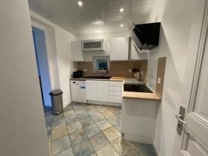 una cucina con armadietti bianchi e pavimento piastrellato di Qouei Eichi la maison fleurie PISCINE Campagne a Bas-en-Basset