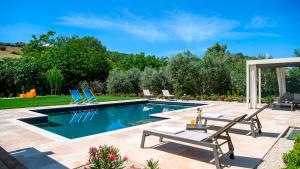 a swimming pool with two chairs and a table at VILLINO LE MOIE 4&2, Emma Villas in Fermo