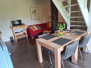 a living room with a wooden table and a red couch at Erve Het Roolvink Boerderij Appartementen 40-50 M2 in Enschede