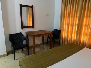 a bedroom with a table and two chairs and a mirror at Why Not Palace in Anuradhapura
