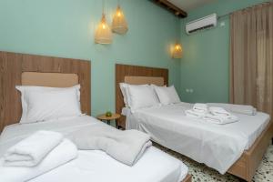 two beds in a room with white sheets and towels at Pteleo Apartments in Pteleos
