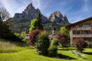 a house in a field with mountains in the background at Artnatur Dolomites Hotel & Spa in Siusi