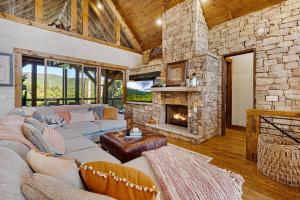 a living room with a couch and a stone fireplace at Copperline Lodge - Luxury Creekside Retreat - Creekside Views, Hot Tub, Game Room, Outdoor Fireplaces, Chef Kitchen, Fire Pit - in Epworth