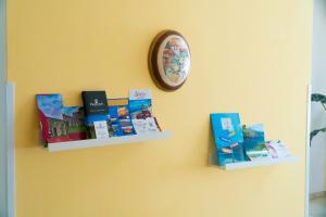 a clock hanging on a wall with books at Ostello Bortone in Castelnuovo Cilento +3 photos