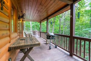 a porch with a wooden bench and a grill at Hibernation Station - Hot Tub, Fireplace, Serene Forest Views - Cherry Log, GA in Blue Ridge