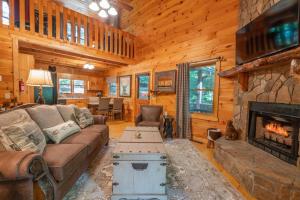 a living room with a couch and a fireplace at Hibernation Station - Hot Tub, Fireplace, Serene Forest Views - Cherry Log, GA in Blue Ridge