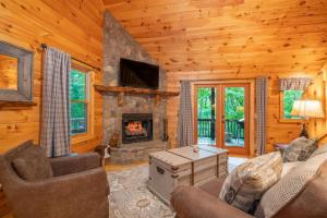 a living room with a fireplace in a log cabin at Hibernation Station - Hot Tub, Fireplace, Serene Forest Views - Cherry Log, GA in Blue Ridge
