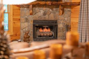 a fireplace in a log cabin with flames in it at Hibernation Station - Hot Tub, Fireplace, Serene Forest Views - Cherry Log, GA in Blue Ridge