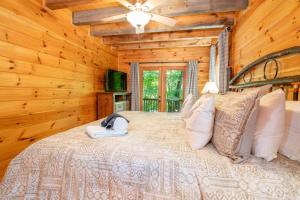 a bedroom with a bed in a log cabin at Hibernation Station - Hot Tub, Fireplace, Serene Forest Views - Cherry Log, GA in Blue Ridge