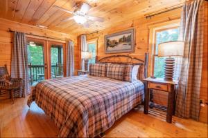 a bedroom with a bed in a log cabin at Hibernation Station - Hot Tub, Fireplace, Serene Forest Views - Cherry Log, GA in Blue Ridge