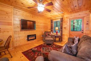 a living room with a couch and a fireplace in a log cabin at Hibernation Station - Hot Tub, Fireplace, Serene Forest Views - Cherry Log, GA in Blue Ridge